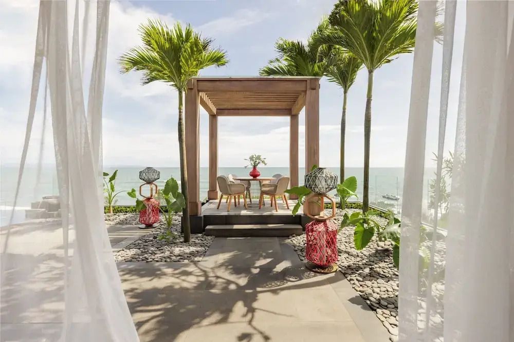 Terrasse mit Sitzbereich unter Pergola und Meerblick umgeben von tropischen Pflanzen