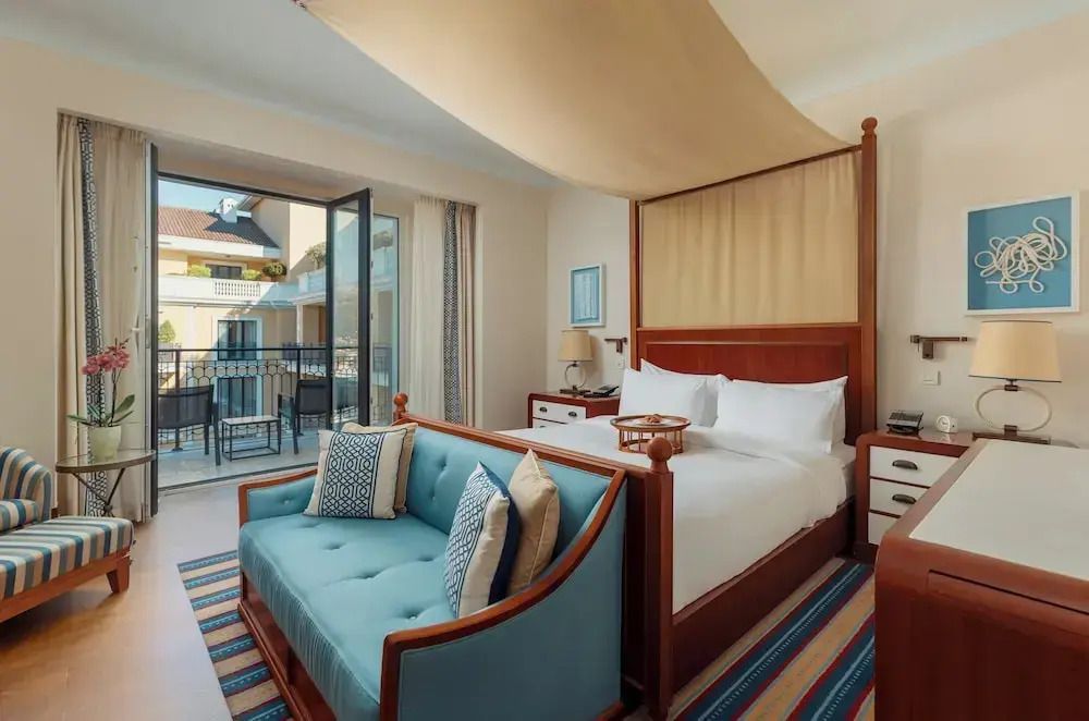 Elegantes Premium Doppelzimmer mit Balkon und eingeschränktem Meerblick, Doppelbett und Sofaecke.