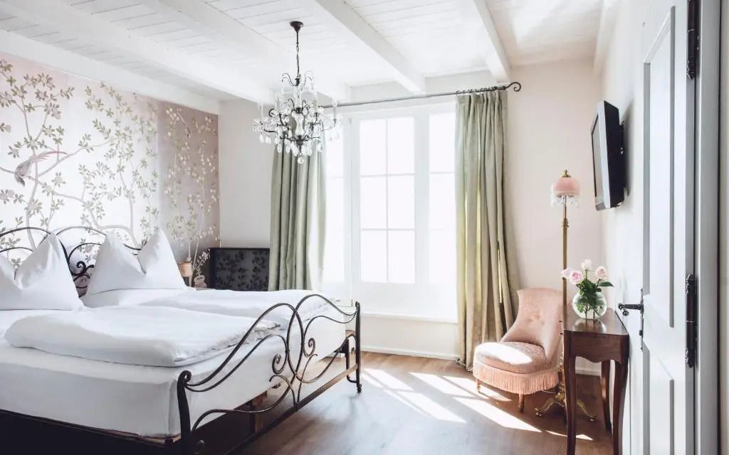 Helles Schlafzimmer mit stilvollem Metallbett und Sitzbereich