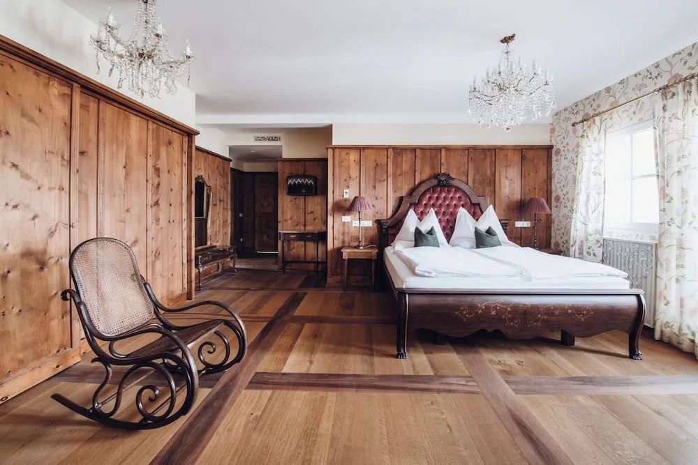 Geräumiges Schlafzimmer mit edlen Holzelementen und Kronleuchtern