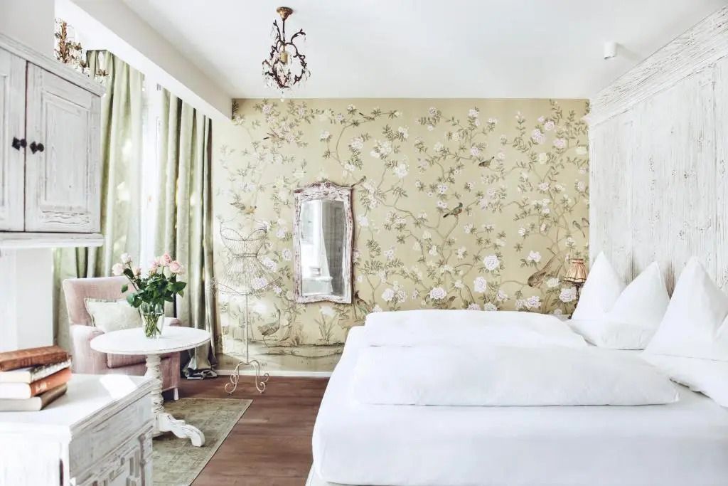 Schlafzimmer mit floralem Wandmuster und edlem Kronleuchter
