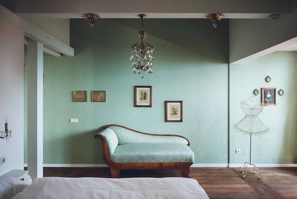 Elegante Chaiselongue in mintgrünem Raum mit Kunstwerken an der Wand