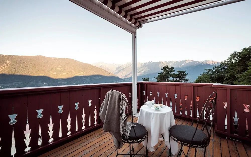 Gemütlicher Balkon mit Blick auf die Alpen und stilvoll gedecktem Tisch