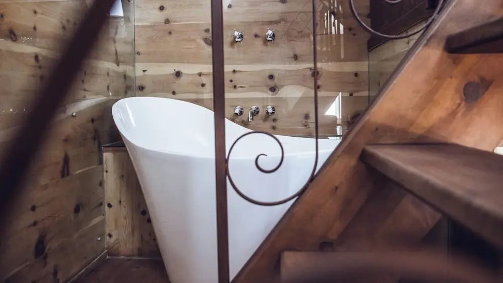 Luxuriöse freistehende Badewanne in einer Suite mit Holzverkleidung