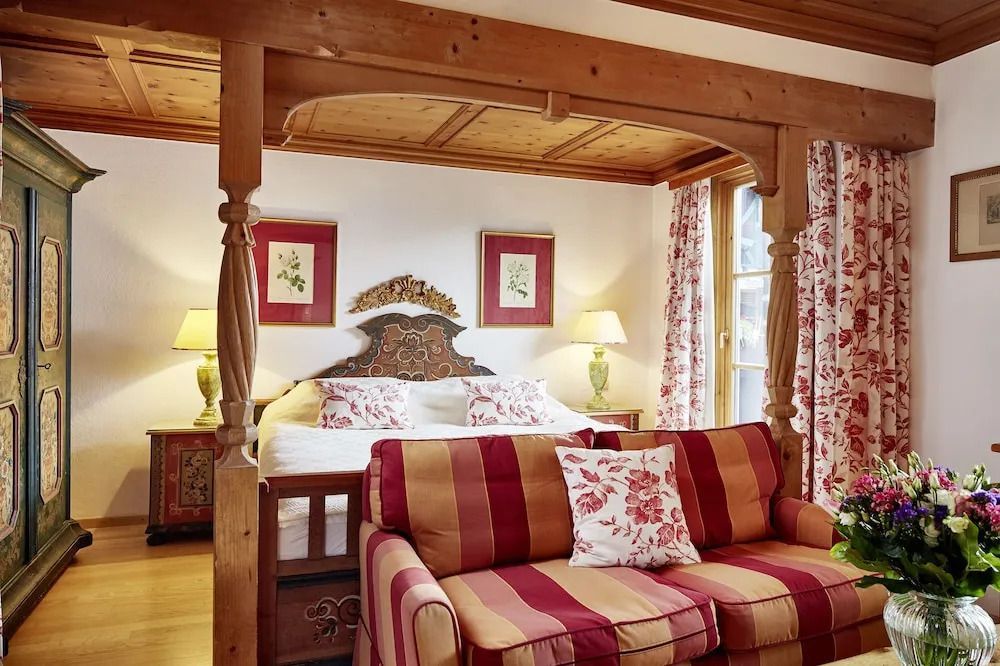 Elegante Suite mit dekorativem Bett und rotem Sofa im alpinen Design