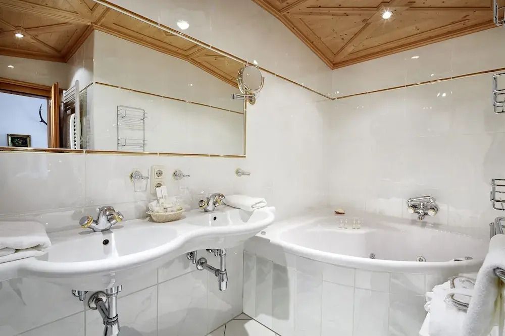 Weißes Badezimmer mit Doppelwaschbecken und runder Badewanne.