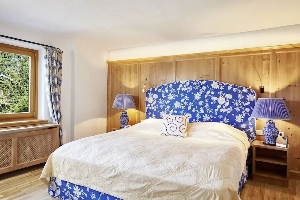 Gemütliches Doppelbett mit blauem Kopfteil und gelber Tagesdecke in der Junior-Suite.