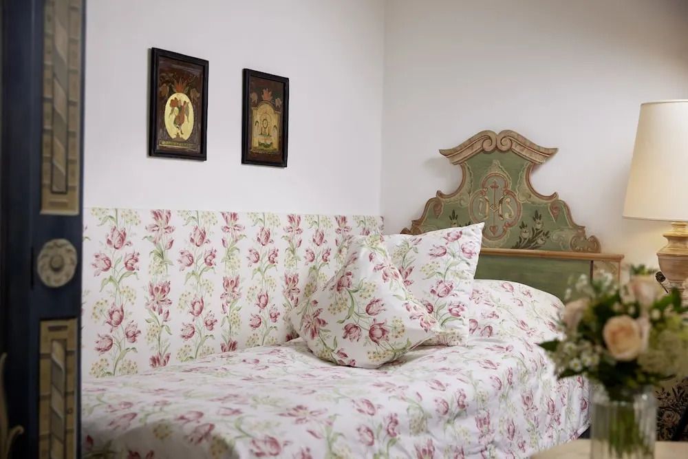 Einzelbett mit floralem Bettbezug und dekorativem Kopfteil
