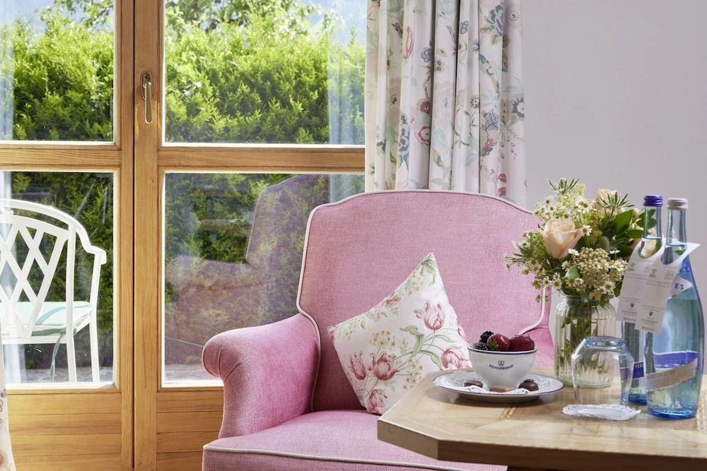 Rosa Polstersessel vor Fenster mit Ausblick auf Garten