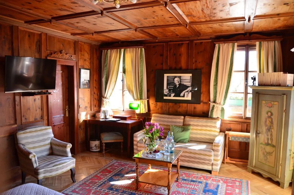 Sitzecke im Premium Zimmer mit Sofa, Schreibtisch und traditionellen Holzwänden.