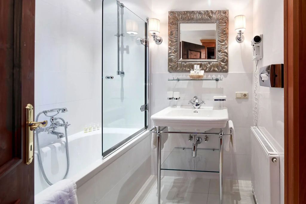 Modernes Badezimmer mit eleganter Badewanne, Glasabtrennung und stilvollem Spiegel.