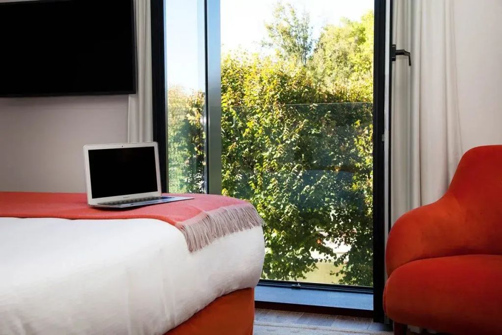 Helles Hotelzimmer mit Doppelbett und Flussblick durch großes Fenster