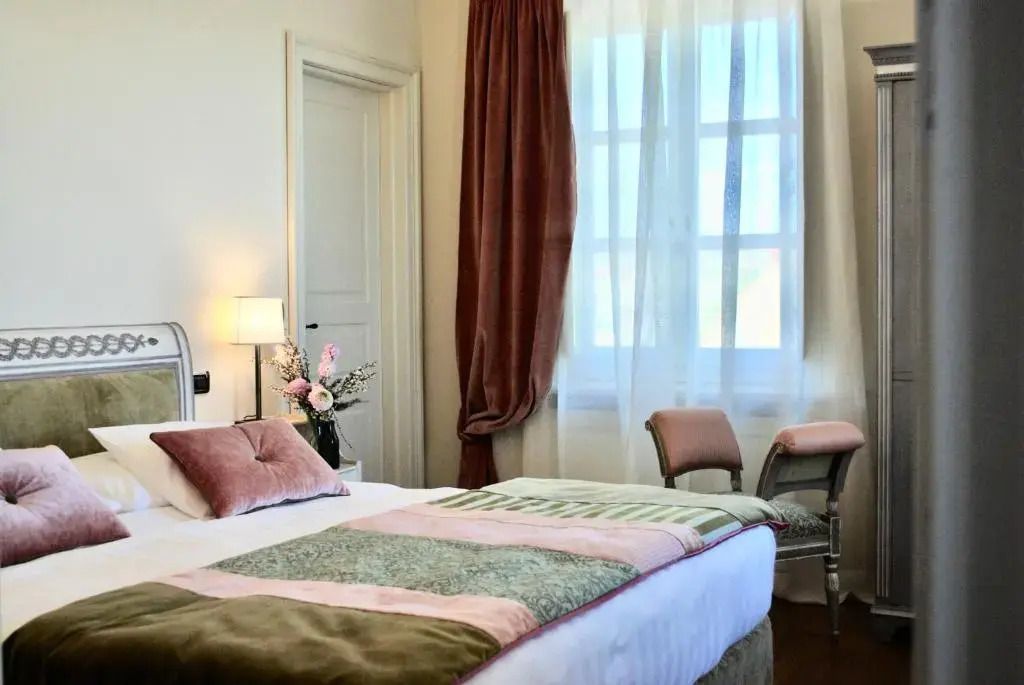 Helles Standard Zimmer mit dekorativen Kissen und Vorhängen im Hotel Relais San Maurizio.