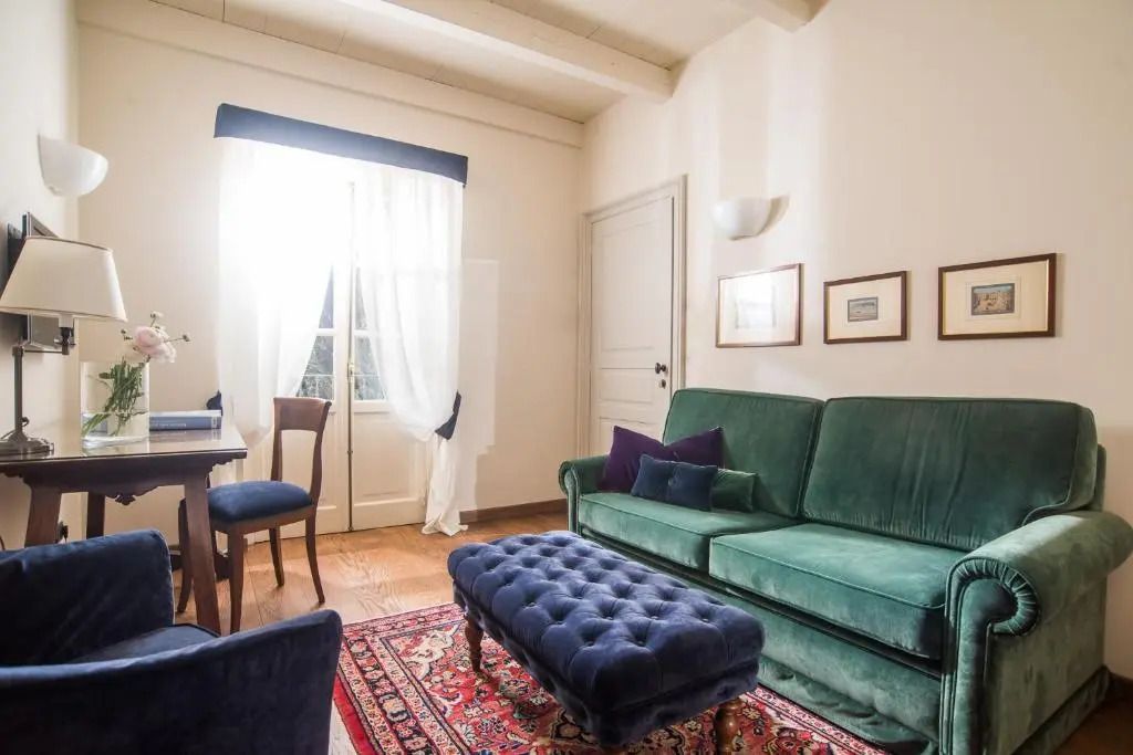 Suite-Wohnbereich mit grünem Sofa, Teppich und hellen Vorhängen