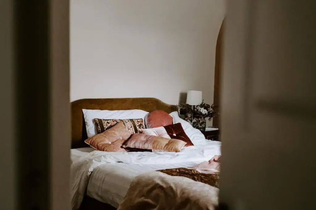 Gemütliches Bett mit dekorativen Kissen und Nachttischlampe