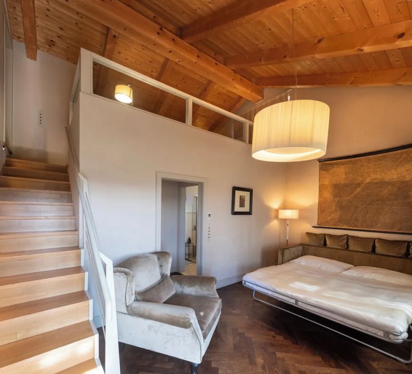 Gemütliches Schlafzimmer im Apartment mit Holzbalkendecke und Treppe zur Galerie