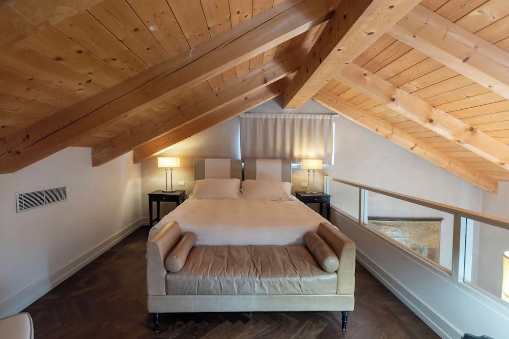 Doppelbett unter Dachschräge mit Holzbalkendecke, elegantes Ambiente