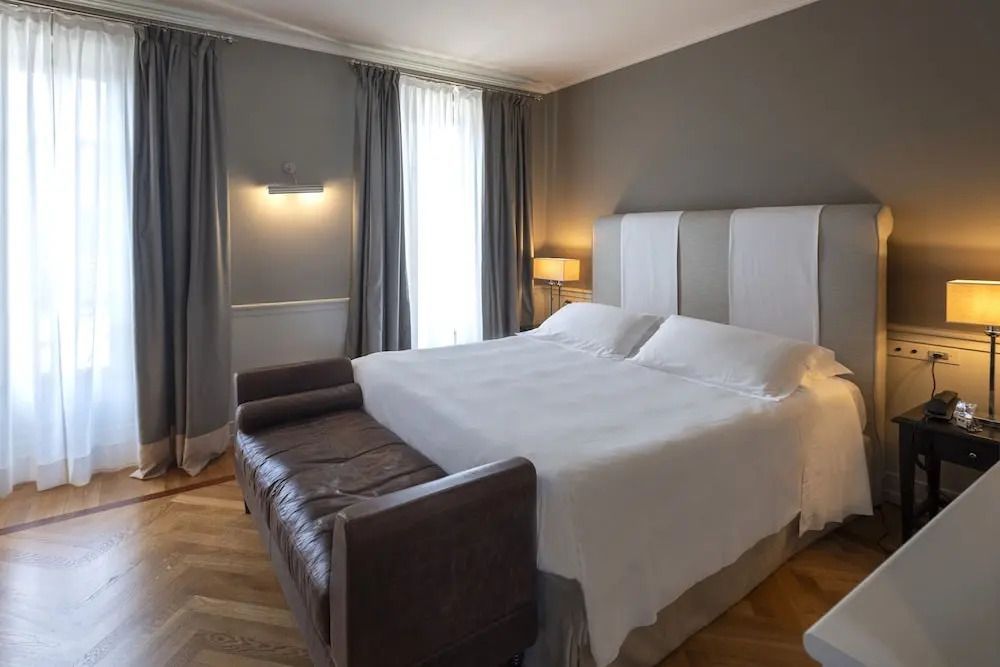 Großes Bett im klassischen Zimmer mit Sofa und Vorhängen