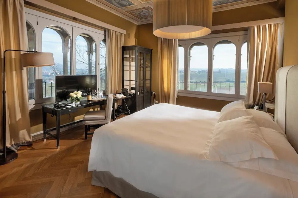 Elegantes Hotelzimmer mit einem großen Bett, Balkonblick auf die Weinberge.