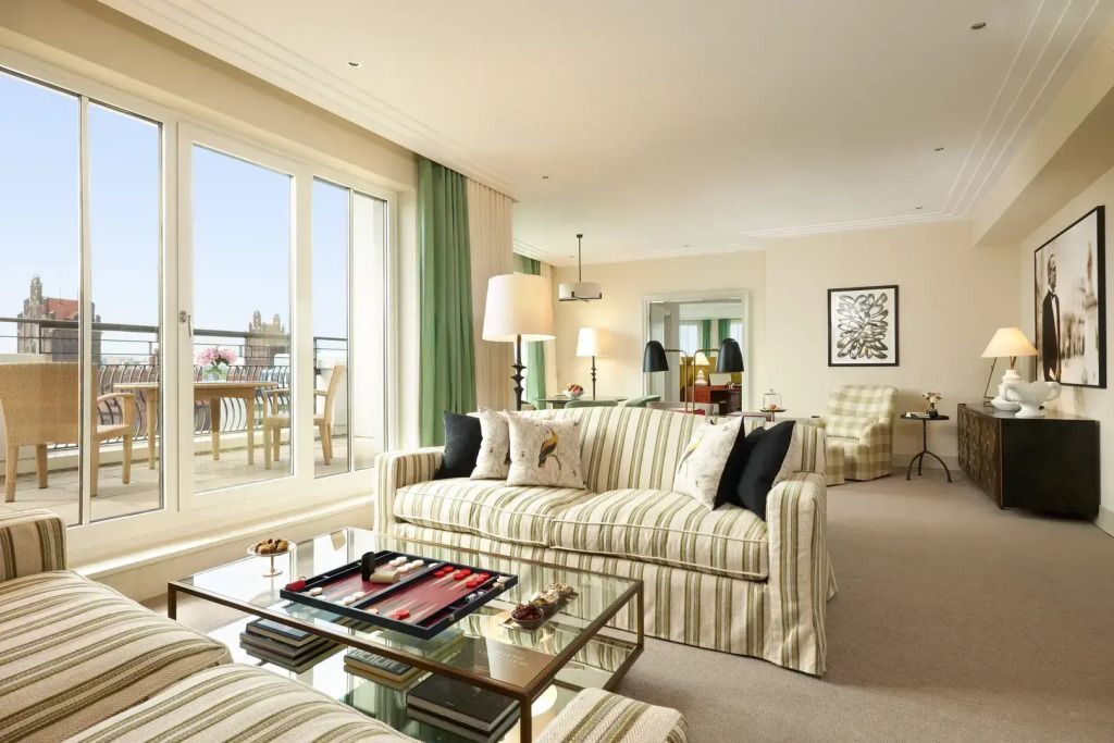 Helles Wohnzimmer mit Streifensofas und Zugang zum Balkon in der Suite.