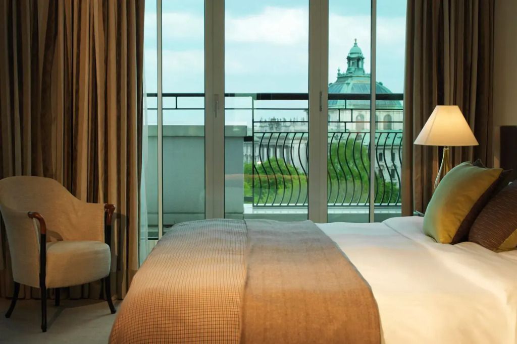Helles Schlafzimmer mit Doppelbett und Balkonblick auf Stadtlandschaft