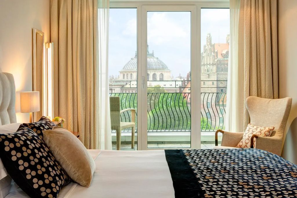 Helles Schlafzimmer mit Doppelbett und Balkonblick auf historische Gebäude