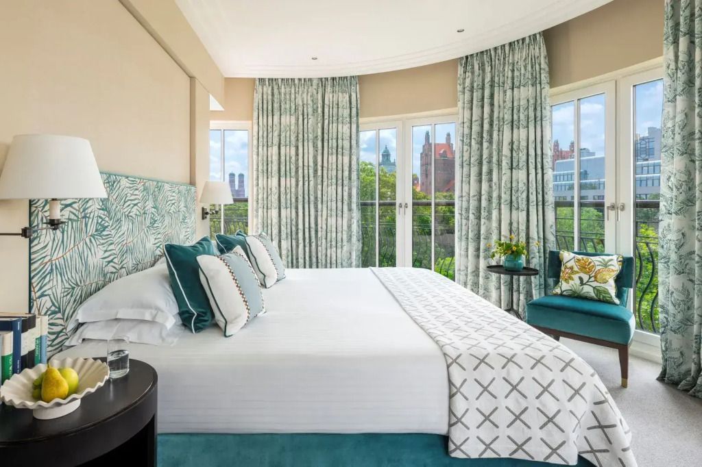 Helles Schlafzimmer mit Doppelbett, großen Fenstern und Blick auf den Park.