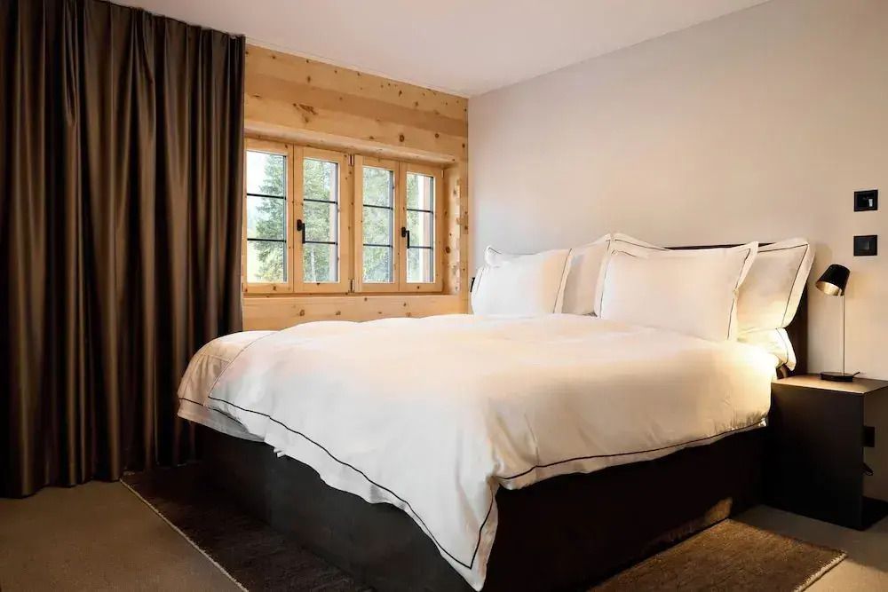 Schlafzimmer mit großem Bett und eleganten Holzwänden sowie Vorhängen.