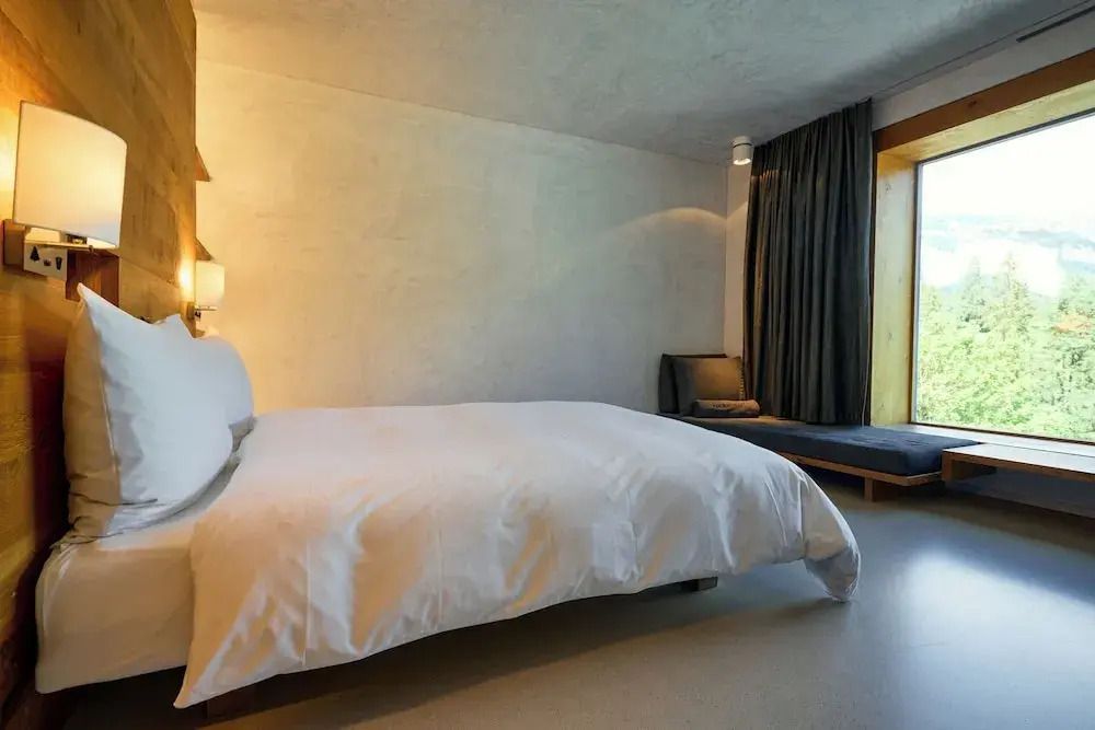Geräumiges Hotelzimmer mit Doppelbett und zusätzlichem Sitzbereich vor großem Fenster