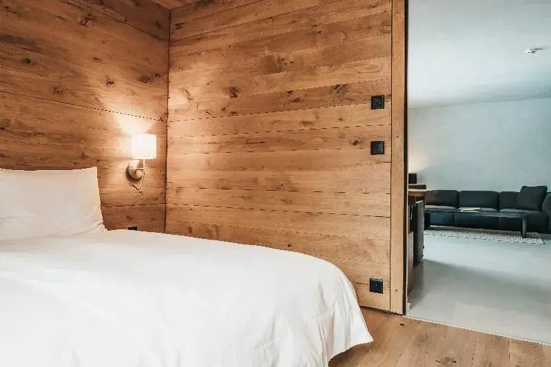 Schlafzimmer mit Holzwänden und weißem Bettzeug