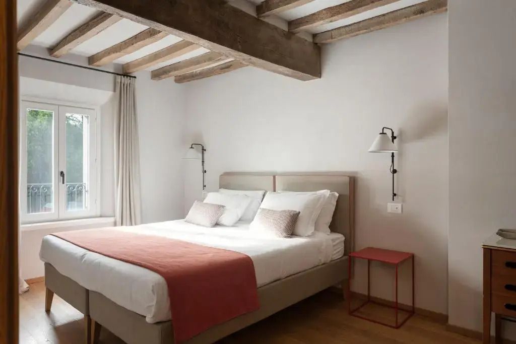 Elegantes Doppelzimmer mit Holzbalkendecke und Doppelbett in dezenten Farben