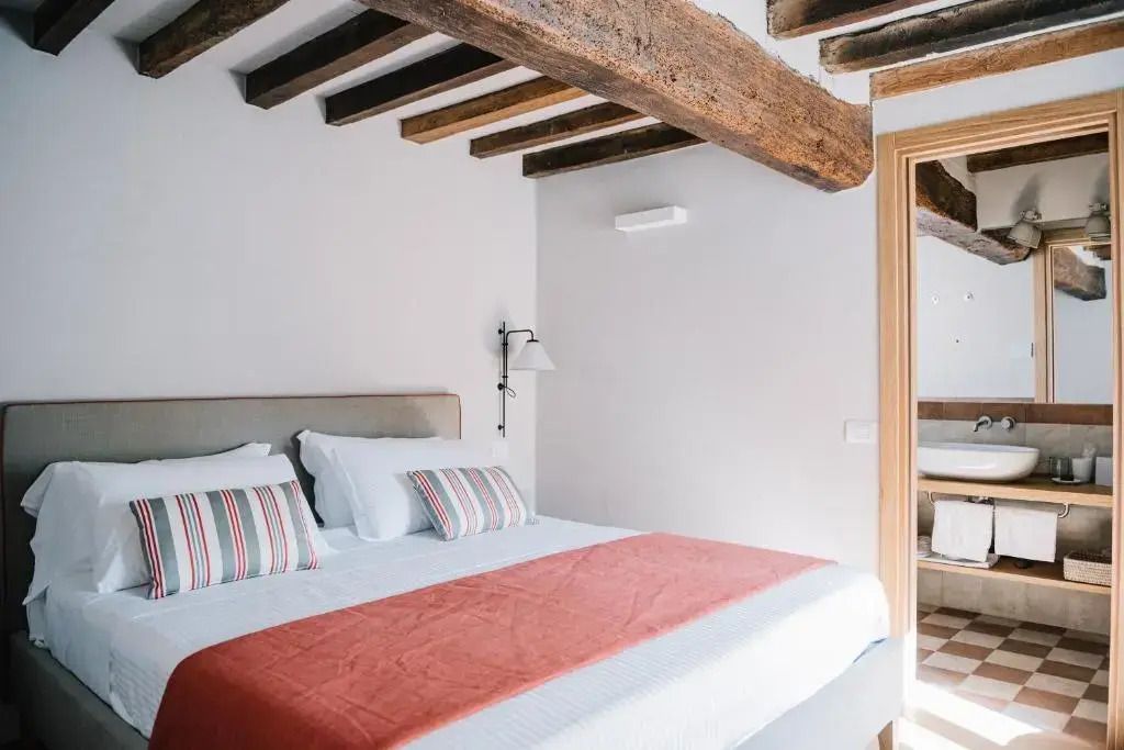 Modernes Doppelzimmer mit Holzbalken und weichen Kissen in sanften Farben