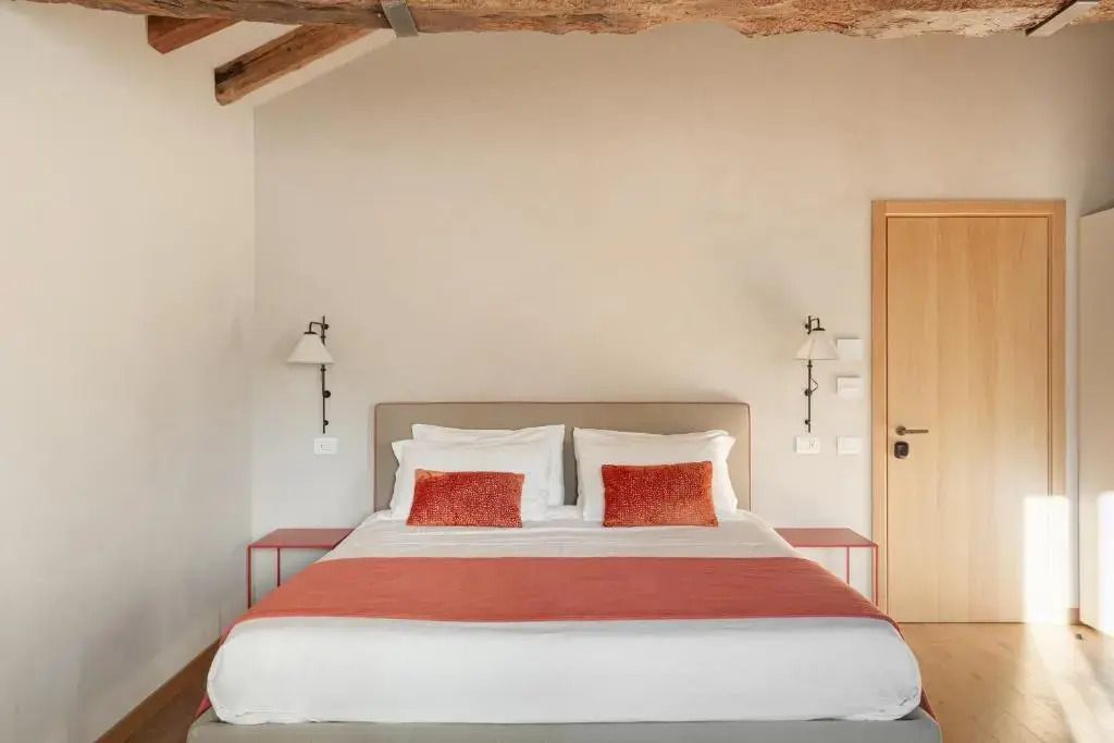 Helles Doppelbett mit Holzbalkendecke und eleganten Kissen in der Dimora Ancini Suite.