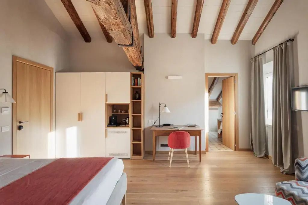 Zimmeransicht mit Schreibtisch und Holzbalkendecke in der Dimora Ancini Suite.