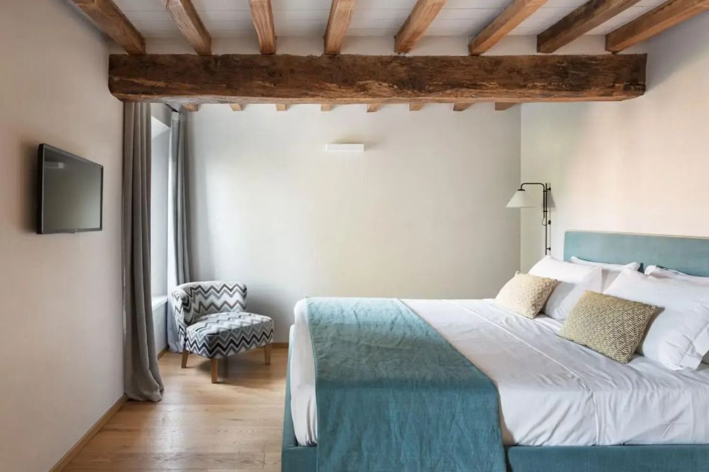 Helles Superior Doppelzimmer mit Holzdecke und elegantem Sessel