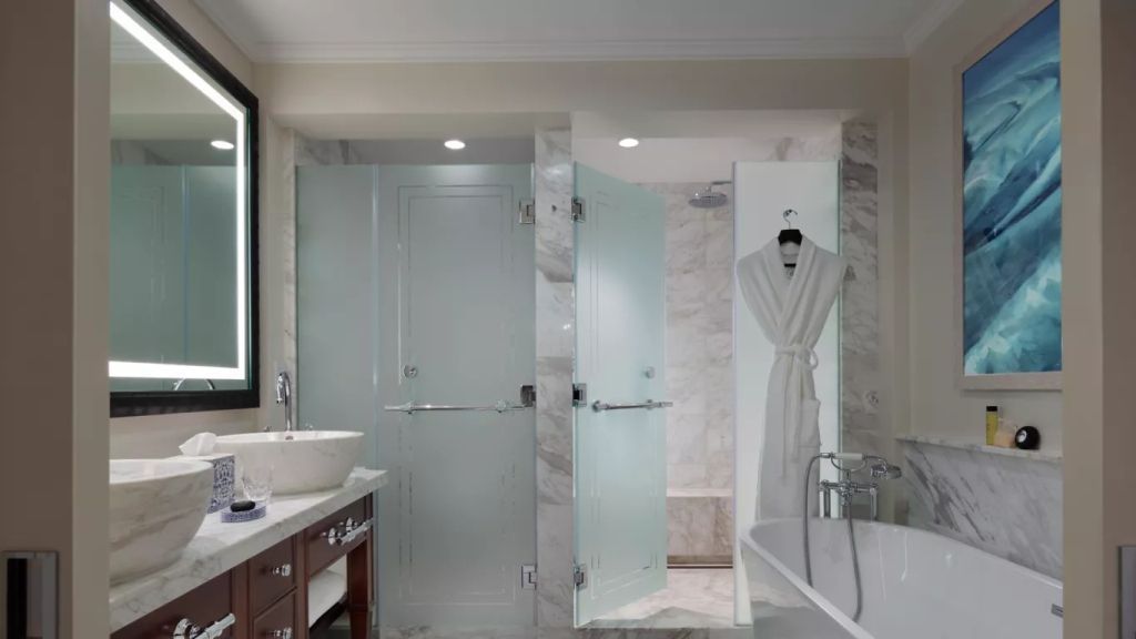 Modernes Badezimmer mit Marmorfliesen, Duschkabine und freistehender Badewanne.