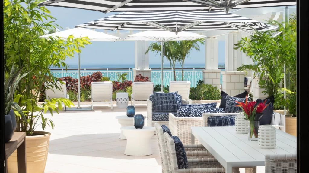 Terrasse mit Meerblick und stilvollen Lounge-Möbeln unter Sonnenschirmen.