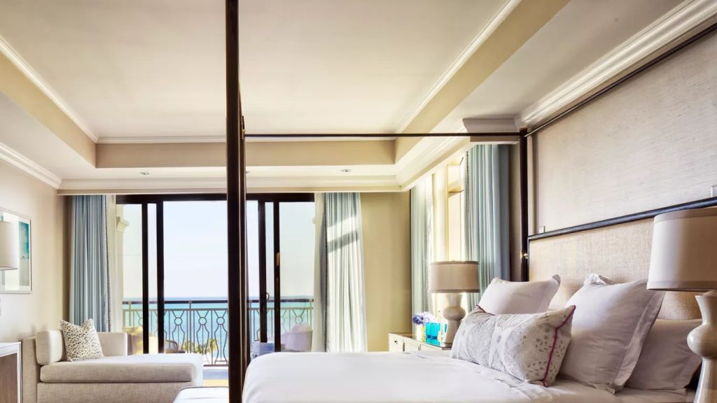 Luxuriöses Schlafzimmer mit Himmelbett und Balkonblick auf das Meer.