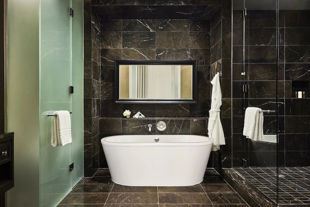 Luxuriöses Badezimmer mit freistehender Badewanne und eleganten dunklen Fliesen