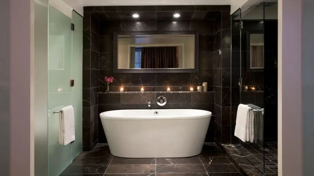 Luxuriöses Badezimmer in dunklem Marmor mit freistehender Badewanne und Kerzen