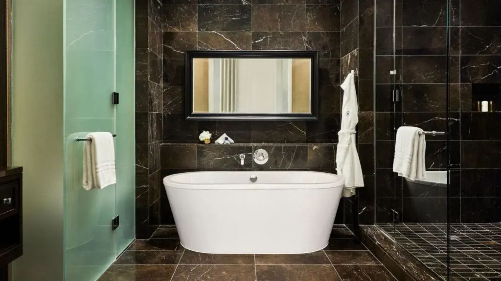 Luxuriöses Badezimmer mit freistehender Badewanne und dunklen Marmorelementen.