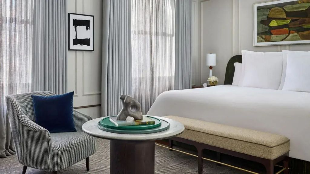 Elegantes Hotelzimmer mit Doppelbett, Kunstwerk an der Wand und stilvollen Möbeln.