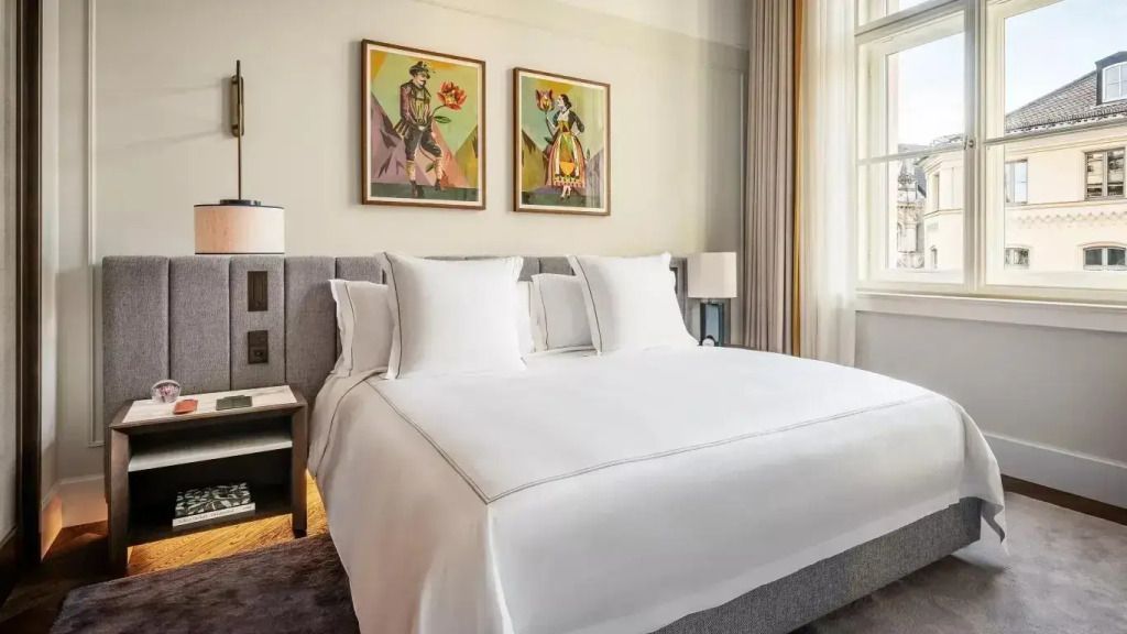 Elegantes Schlafzimmer mit großem Doppelbett und zwei Kunstwerken an der Wand