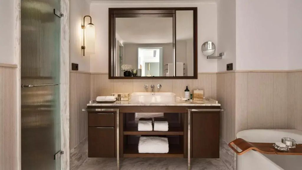 Modernes Badezimmer mit großzügigem Waschbecken und großen Spiegel im Hotelzimmer.
