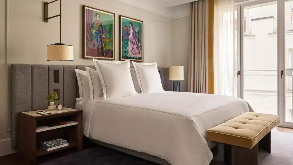 Helles Schlafzimmer mit luxuriösem Doppelbett und Kunstwerken an der Wand
