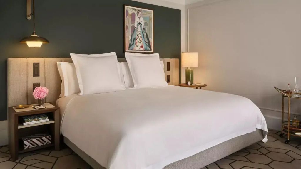 Elegantes Hotelzimmer mit weißem Doppelbett und stilvollem Wandbild.