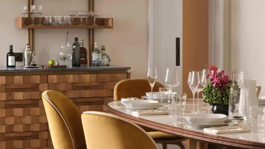Eleganter Esstisch mit goldenen Stühlen und Bar im Hintergrund