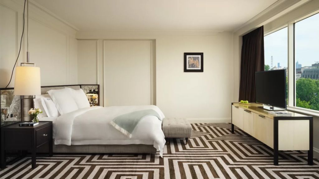 Elegantes Schlafzimmer einer Junior-Suite mit Doppelbett und kunstvollem Teppichmuster.