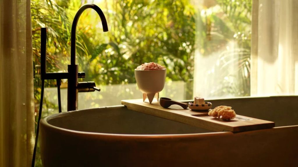 Freistehende Badewanne im Spa-Ambiente mit Blick auf grüne Vegetation