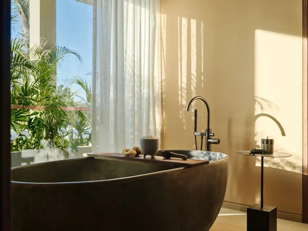 Luxuriöse freistehende Badewanne vor Fenster mit Blick auf Natur
